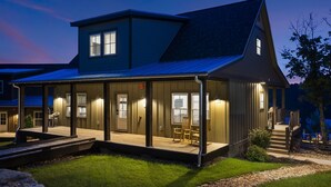 A two-story house with a covered porch and a small deck, featuring a large window and a door. - Poolside Cabin #12 (3 bedroom, pickle ball, playground, perfect family stay!) (Kimberling City)