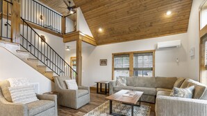 A spacious living area with a wooden staircase, a sofa set, a coffee table, and a patterned rug. - Poolside Cabin #12 (3 bedroom, pickle ball, playground, perfect family stay!) (Kimberling City)