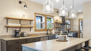 A modern kitchen with wooden shelves, a central island, and pendant lighting. - Poolside Cabin #12 (3 bedroom, pickle ball, playground, perfect family stay!) (Kimberling City)