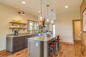 A spacious kitchen with a large island, wooden flooring, and pendant lighting.
