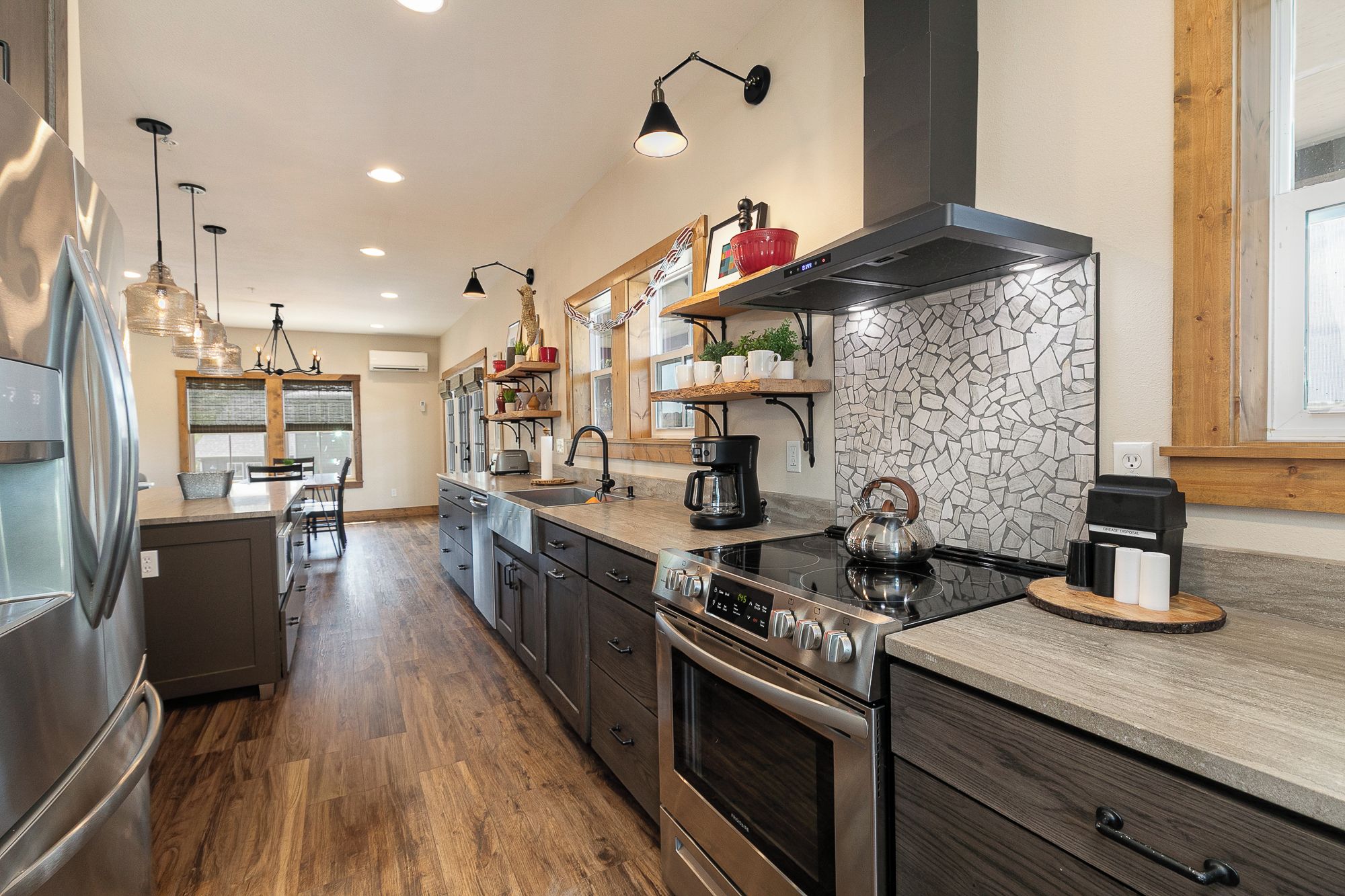 A modern kitchen with stainless steel appliances, a large island, and a stone backsplash.