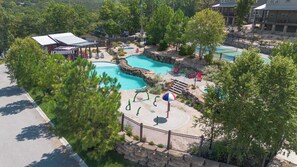 A resort with multiple swimming pools, a playground, and a fenced area with lounge chairs.