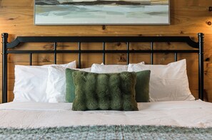 Una cama con cabecera, almohadas y manta.