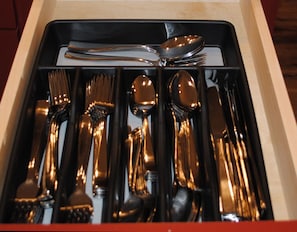 A drawer containing neatly arranged silverware including forks, spoons, and knives.