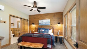A bedroom with a bed, bedside tables, a bench, a ceiling fan, and a painting on the wall. - Poolside Cabin #13 Luxury 3 bedroom - Perfect Family Retreat for 8 people. (Kimberling City)
