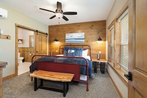 A bedroom with a bed, bedside tables, a bench, a ceiling fan, and a painting on the wall. - Poolside Cabin #13 Luxury 3 bedroom - Perfect Family Retreat for 8 people. (Kimberling City)