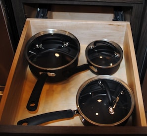 A drawer with three black pots of varying sizes.