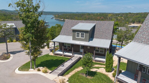 A two-story house with a covered porch, a small deck, and a view of a lake.