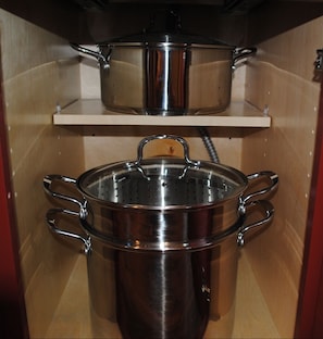 A kitchen with stainless steel cookware on shelves.