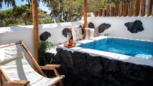 Zona de piscina con una silla de madera, una botella de vino y una mesita.