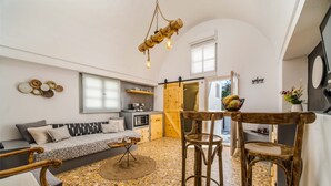 Un espacio habitable compacto con cocina, un área de comedor con sillas de madera, un sofá y una lámpara colgante.