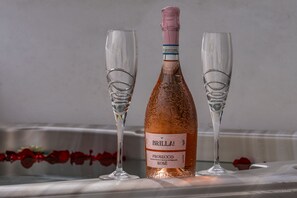 A bottle of Brilla! Prosecco Rosé and two glasses on a table.