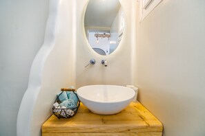 A bathroom with a white sink, wooden countertop, and a mirror above the sink.