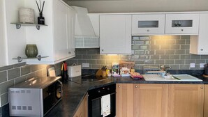 A modern kitchen with white cabinets, a black oven, a microwave, and a sink. - Serendipity- Romantic 1-bed Apt Ambleside (Ambleside)