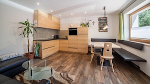 Una cucina moderna con armadietti in legno, una zona pranzo con una panca, un divano e un tavolo in vetro.