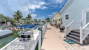 A marina with boats docked, a house with a porch, and a clear sky.