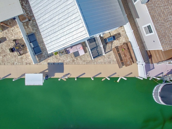 Vista aérea de una propiedad con piscina, mobiliario exterior y un patio cubierto.