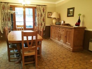 Ein Essbereich mit Holztisch und -stühlen, einer Schrank mit Schubladen und einem Fliesenboden.
