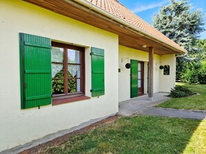 Un bâtiment à la façade jaune, aux volets verts et au toit recouvert de tuiles.