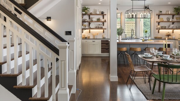 A spacious interior with a wooden staircase, a dining area with a chandelier, and a kitchen with shelves. - The "Idea House" From TV Series This Old House! High End, Definition of Luxury! (Narragansett)