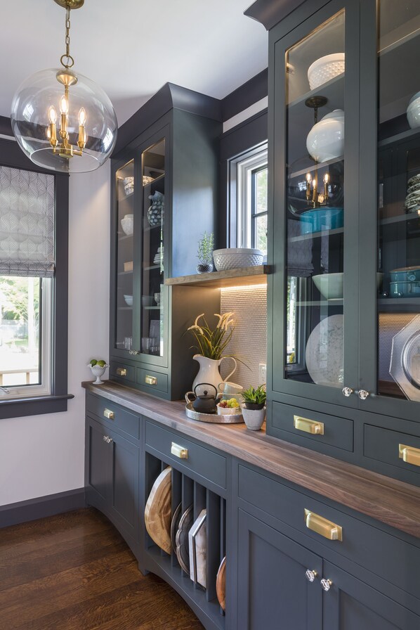 A kitchen with dark cabinetry, a wooden countertop, and a hanging light fixture.