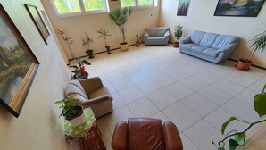 A spacious living room with a brown leather chair, a grey sofa, and several potted plants. - Gabriel (Maardu)