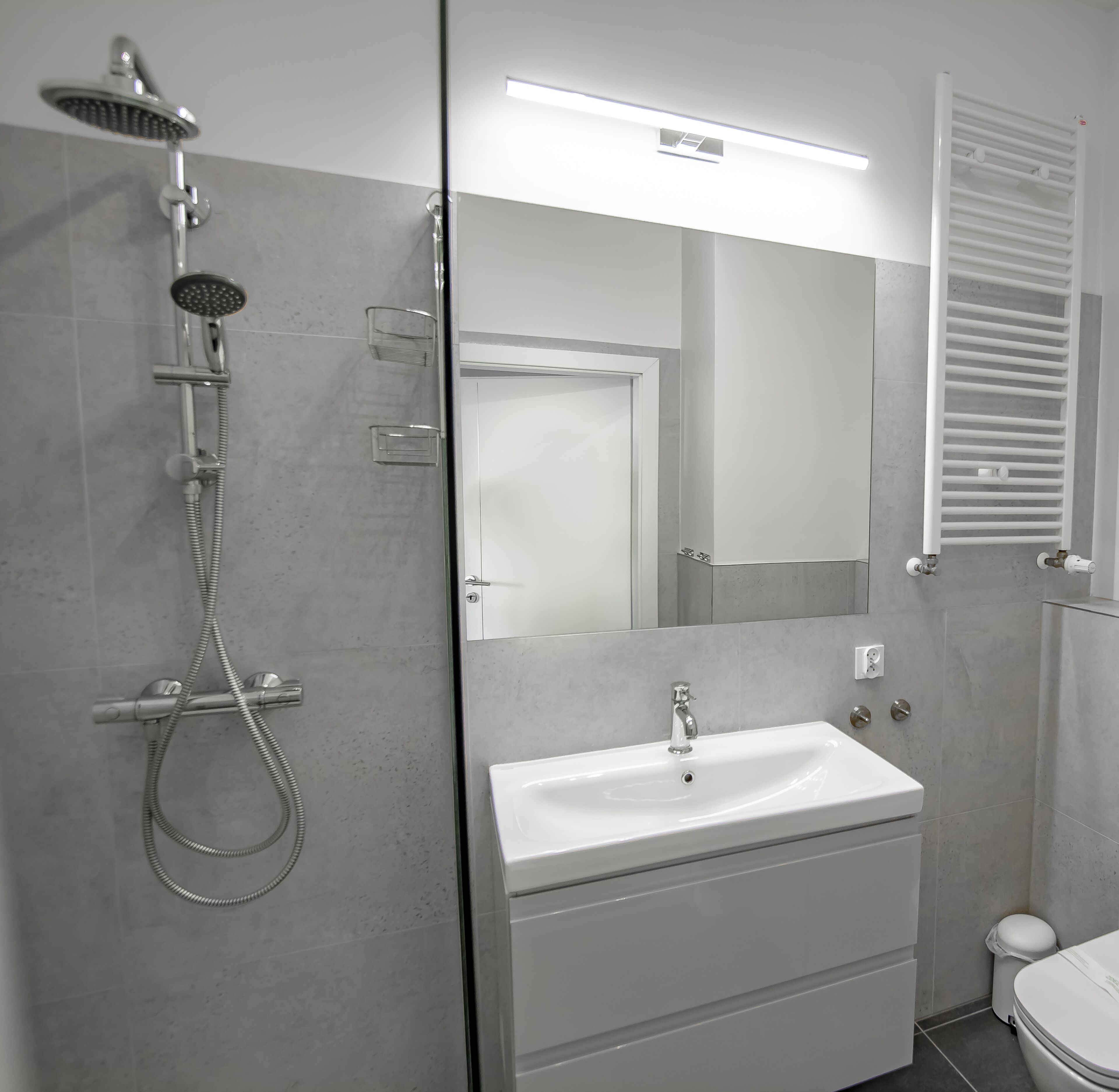 A modern bathroom with a shower, sink, and toilet.