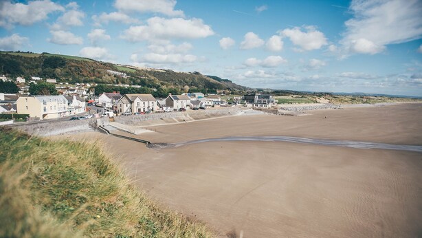 A coastal town with a sandy beach, houses, and a grassy hill in the background. - Perfect romantic break-  cottage in Laugharne (Laugharne)