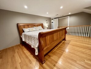 A bedroom with a wooden bed, a nightstand, and a window with blinds.