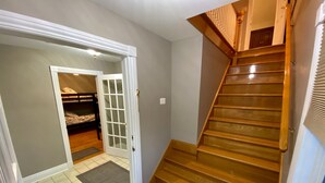 Eine Treppe führt zu einer zweiten Etage, eine Tür mit Glasfenstern und ein Etagenbett in einem Flur.