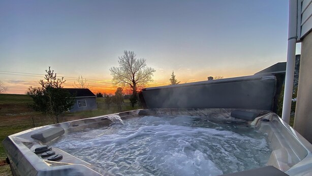 Ein Whirlpool mit Blick auf einen Sonnenuntergang und ein Haus im Hintergrund.