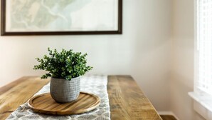 Una planta en maceta sobre una bandeja de madera en una mesa con un mantel tejido.