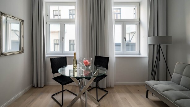 Un comedor moderno con una mesa de vidrio, sillas negras y un sofá.