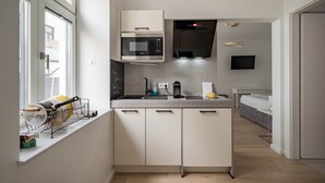 Una cocina moderna con microondas integrado, horno y cocina a gas. Hay una ventana con vistas al exterior, un lavamanos y una encimera con hervidor y cafetera.