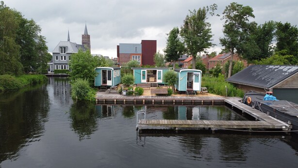 Een object aan het water met drijvende huizen, verbonden door een houten steiger.