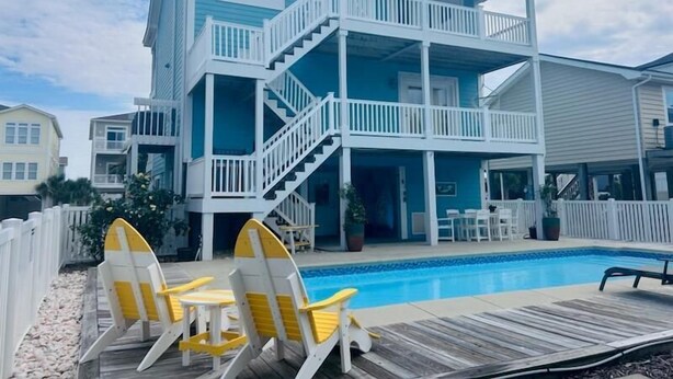 A two-story beachfront house with a pool, deck chairs, and a covered patio. - 218 Brunswick in Holden Beach, perfect for family getaways! (Holden Beach)
