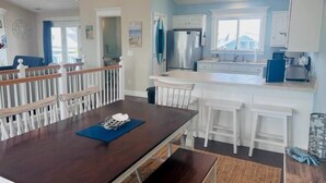 A modern kitchen with white cabinets, a stainless steel refrigerator, and a blue countertop. - 218 Brunswick in Holden Beach, perfect for family getaways! (Holden Beach)