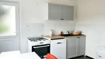 Een kleine keuken met een gasfornuis, vaatwasser en een klein aanrecht.