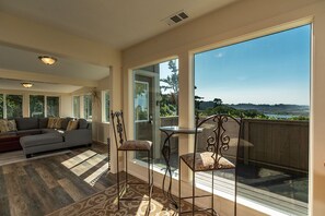 A spacious living room with a large sofa, two chairs, and a view of a scenic landscape through large windows. - Moonstone Beach Retreat - Beach Lover's Getaway! (Trinidad)