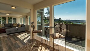 Ein geräumiges Wohnzimmer mit einer großen Couch, zwei Sesseln und Blick auf eine reizvolle Landschaft durch große Fenster.