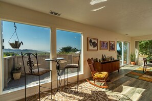 A spacious balcony with a view of the landscape, a dining area with a table and chairs, and a seating area with a rocking chair. - Moonstone Beach Retreat - Beach Lover's Getaway! (Trinidad)