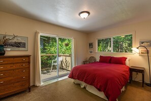 A bedroom with a large bed, a dresser, and a sliding glass door leading to a balcony. - Moonstone Beach Retreat - Beach Lover's Getaway! (Trinidad)