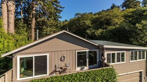 Ein Bungalow mit einer großen Schiebetür aus Glas, einer überdachten Terrasse mit Gartenmöbeln und einer Garage.