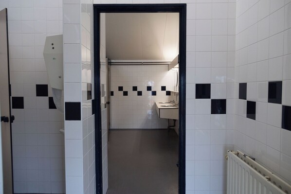 A narrow hallway with white tiled walls and a black door frame.