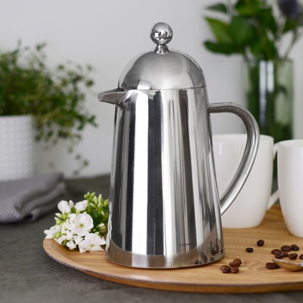 A stainless steel coffee pot on a wooden board with white flowers and coffee beans. - Loxley Barn, 1-bed Cottage Retreat (Tring)