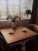 Una mesa de madera para comer con dos platitos y un florero con flores.