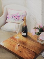 Una mesa de madera con una botella de champán, una copa y un arreglo floral.