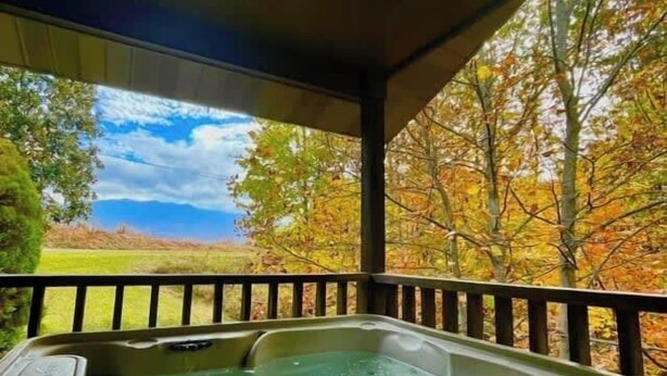 A hot tub with a view of autumn foliage and a clear sky.