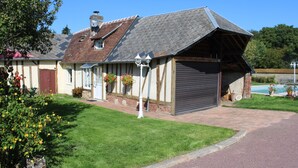 A two-story house with a sloped roof, a garage, and a well-maintained lawn. - Detached house in an 18th-century property. (Mesnil-en-Ouche)