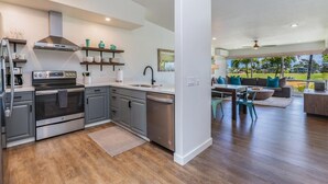 Een moderne keuken met grijze kastjes, roestvrijstalen apparatuur en een eethoek met een houten tafel en stoelen.